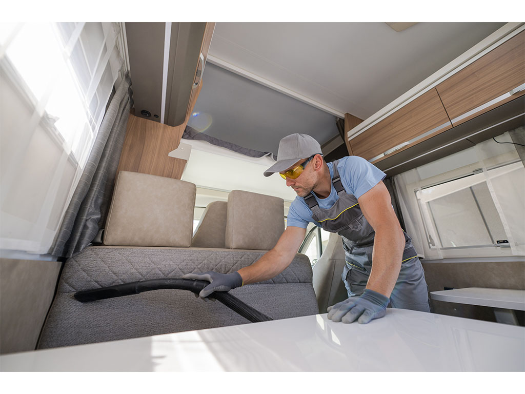CLEANING_0000s_0003_cleaning-services-worker-vacuuming-the-rv-furnitur-2022-12-16-11-47-10-utc